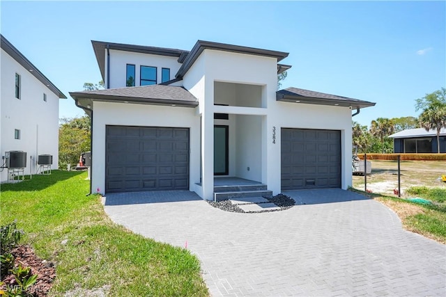 3384 Canal St, Naples, FL 34112 - contemporary home with a front lawn, an attached garage, stucco siding, and cooling unit