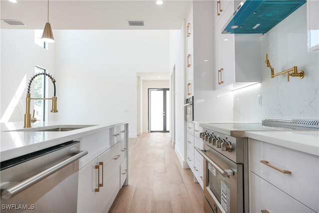 3384 Canal St, Naples, FL 34112 - kitchen featuring a sink, white cabinets, under cabinet range hood, light countertops, and appliances with stainless steel finishes