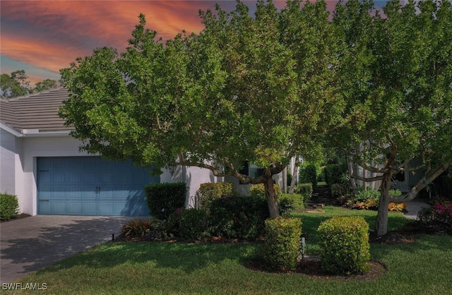 view of front facade featuring a tiled roof, a front lawn, driveway, and stucco siding