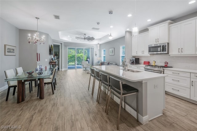 kitchen with light wood-type flooring, recessed lighting, appliances with stainless steel finishes, a sink, and open floor plan
