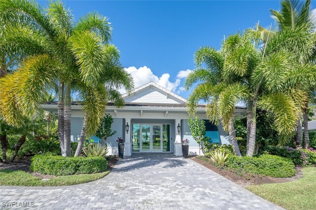 entrance to property featuring french doors, decorative driveway, and stucco siding