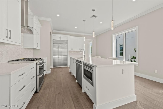 1134 Trail Terrace Dr, Naples, FL 34103 - kitchen featuring crown molding, wood finished floors, wall chimney exhaust hood, a sink, and built in appliances