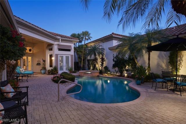 view of pool with a patio area, a pool with connected hot tub, and french doors