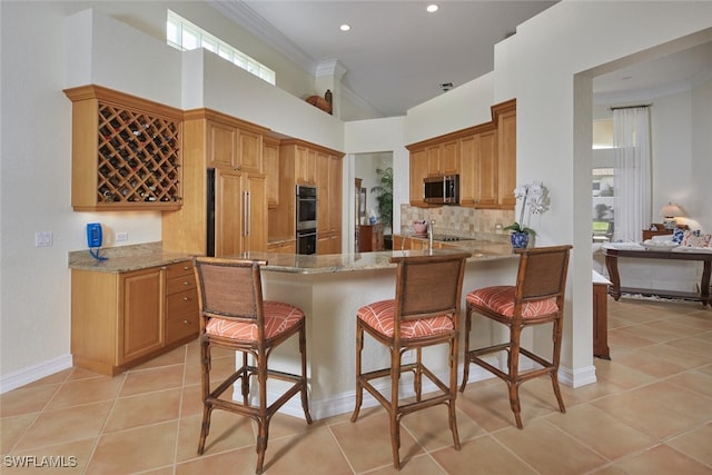 kitchen with stainless steel appliances, light stone countertops, light tile patterned floors, and ornamental molding