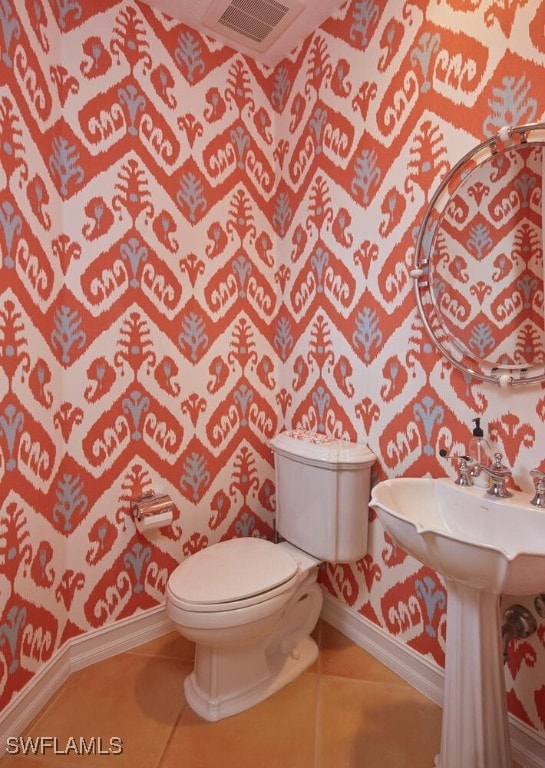 half bathroom featuring toilet, visible vents, tile patterned floors, and baseboards