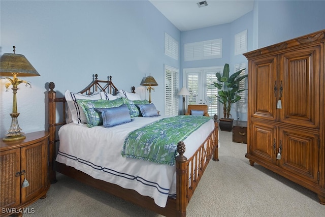 bedroom with french doors, light colored carpet, a high ceiling, and visible vents