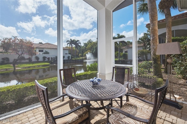 sunroom featuring expansive windows, stone tile flooring, and a water view