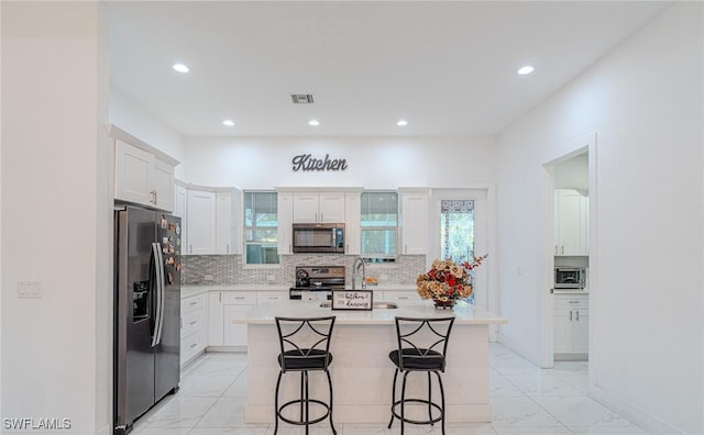 233 39th Ave NE, Naples, FL 34120 - kitchen featuring stainless steel appliances, a breakfast bar area, white cabinets, light countertops, and backsplash
