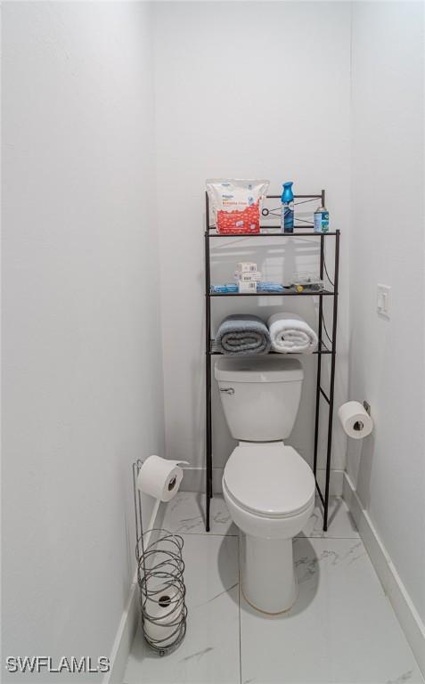 233 39th Ave NE, Naples, FL 34120 - bathroom featuring marble finish floors, baseboards, and toilet