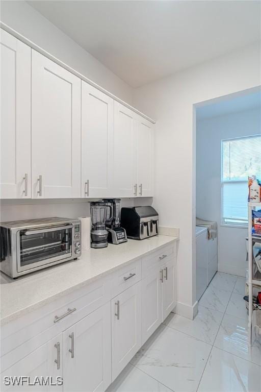 233 39th Ave NE, Naples, FL 34120 - kitchen featuring washer and clothes dryer, light marble finish flooring, white cabinets, and light countertops