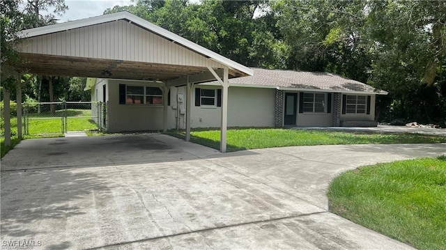 310 S Elm St, Labelle, FL 33935 - single story home featuring stucco siding, driveway, a front yard, a gate, and a carport