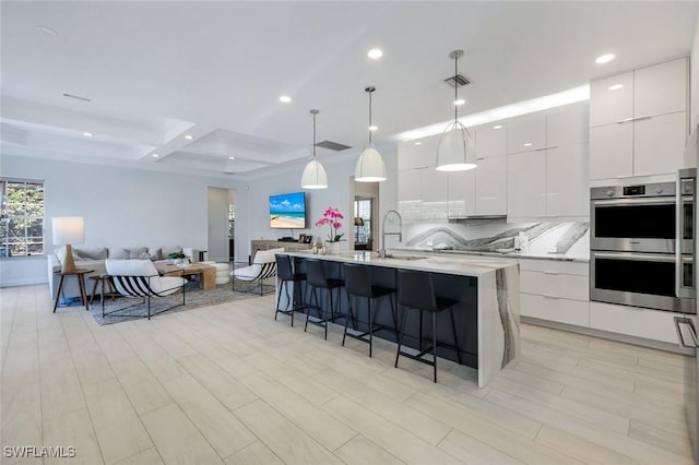 16017 Delarosa Ln, Naples, FL 34110 - kitchen featuring stainless steel double oven, a breakfast bar, a sink, modern cabinets, and open floor plan