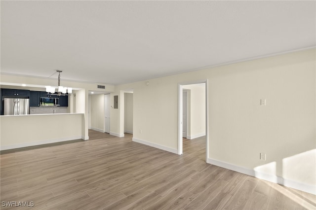 1501 Middle Gulf Dr Unit I-101, Sanibel, FL 33957 - unfurnished living room featuring light wood finished floors, baseboards, visible vents, and an inviting chandelier