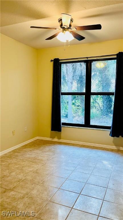 7725 Woodbrook Cir Unit 3503, Naples, FL 34104 - spare room featuring light tile patterned floors, ceiling fan, and baseboards