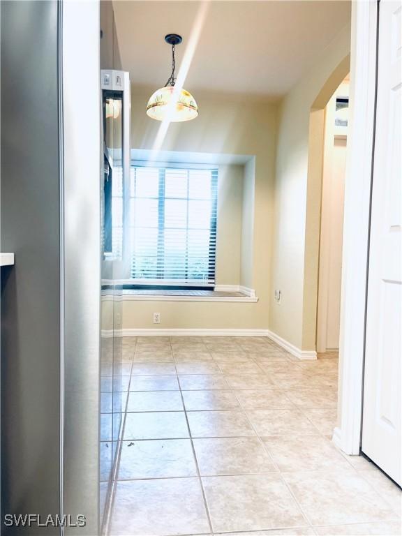 7725 Woodbrook Cir Unit 3503, Naples, FL 34104 - spare room featuring light tile patterned flooring, arched walkways, and baseboards