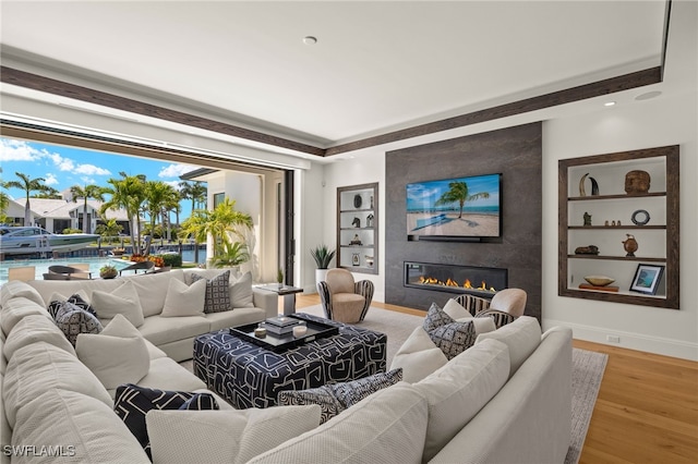 living area with baseboards, wood finished floors, and a large fireplace