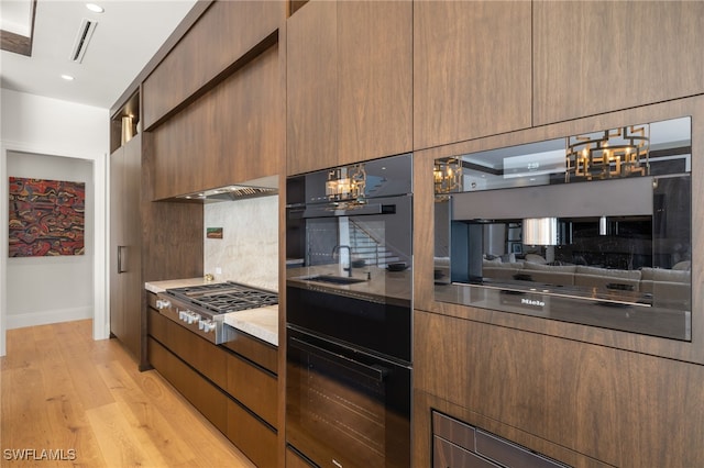 kitchen featuring stainless steel gas stovetop, modern cabinets, backsplash, a notable chandelier, and visible vents