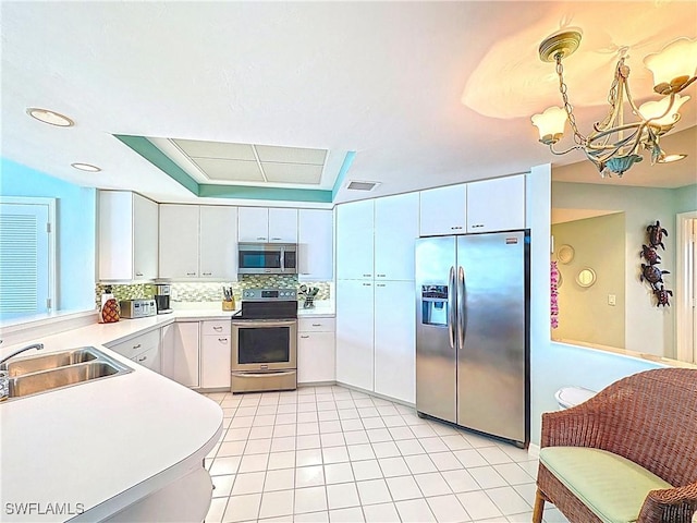kitchen featuring light countertops, appliances with stainless steel finishes, a sink, an inviting chandelier, and backsplash