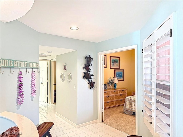 hall featuring baseboards and light tile patterned floors