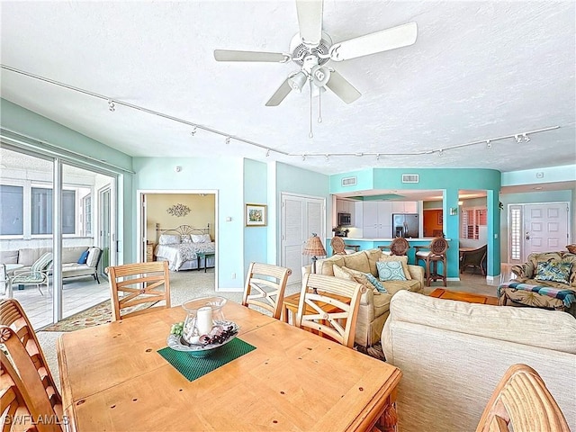 dining room with track lighting, ceiling fan, and a textured ceiling