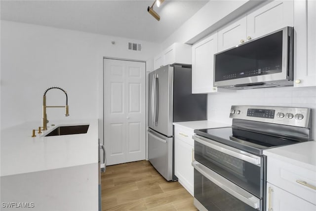 kitchen with white cabinetry, visible vents, light countertops, a sink, and stainless steel appliances