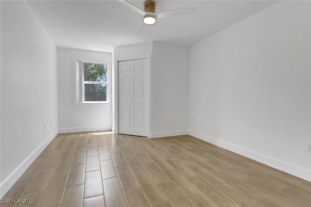 empty room featuring light wood-style flooring, baseboards, and a ceiling fan