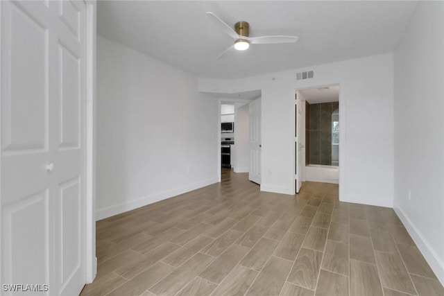 empty room featuring light wood-style flooring, baseboards, a ceiling fan, and visible vents