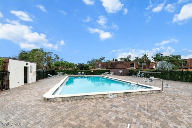 community pool with a patio area and fence