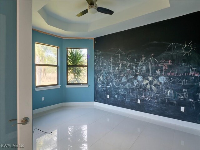 4324 22nd Ave SE, Naples, FL 34117 - unfurnished room featuring a ceiling fan, a tray ceiling, baseboards, and tile patterned floors