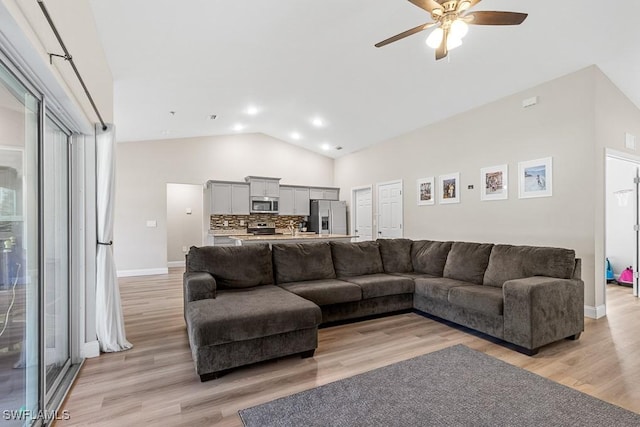 living area with high vaulted ceiling, baseboards, light wood-style floors, and ceiling fan