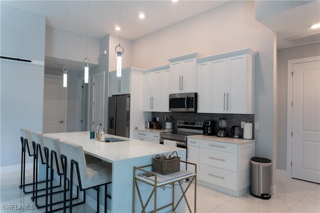 kitchen with decorative backsplash, visible vents, marble finish floor, stainless steel appliances, and a breakfast bar area
