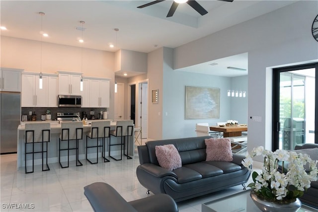 living area with a towering ceiling, ceiling fan, and recessed lighting