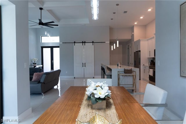 dining space with a ceiling fan, a towering ceiling, and baseboards