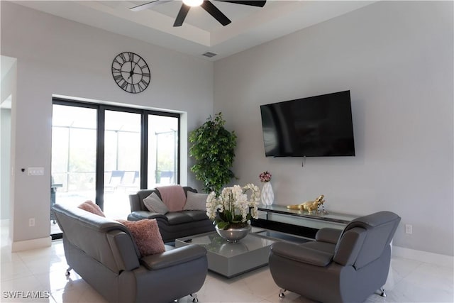living area featuring baseboards, visible vents, a raised ceiling, and a ceiling fan