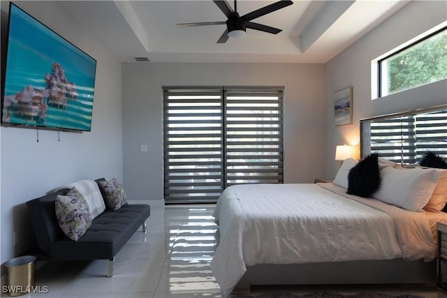 bedroom with a raised ceiling, visible vents, and ceiling fan