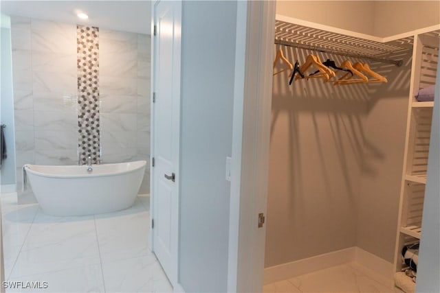 full bathroom featuring marble finish floor, recessed lighting, tile walls, and a freestanding bath