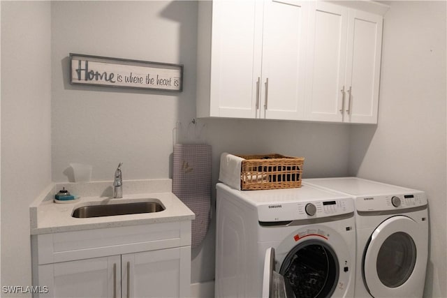 washroom featuring washing machine and clothes dryer, cabinet space, and a sink