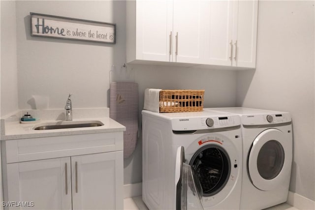 clothes washing area with washing machine and clothes dryer, cabinet space, and a sink