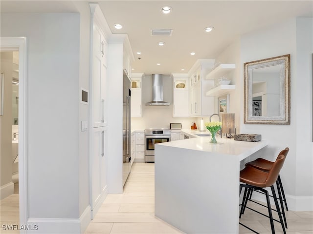 365 5th Ave S Unit 307, Naples, FL 34102 - kitchen with wall chimney exhaust hood, stove, a peninsula, a sink, and white cabinetry
