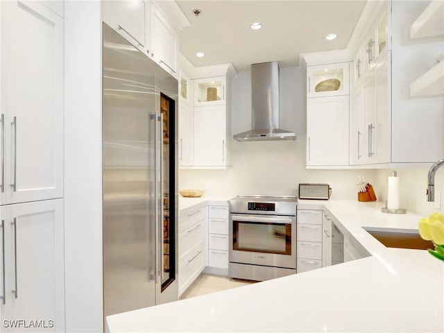 365 5th Ave S Unit 307, Naples, FL 34102 - kitchen featuring appliances with stainless steel finishes, wall chimney exhaust hood, a sink, white cabinets, and recessed lighting