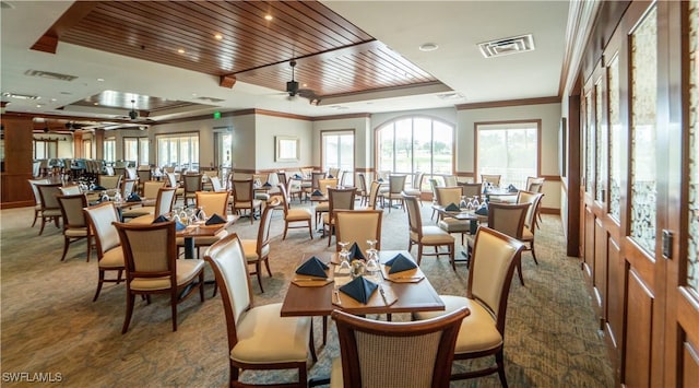 carpeted dining space with a tray ceiling, ceiling fan, plenty of natural light, and crown molding