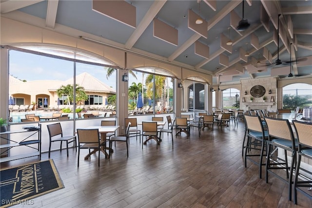 dining area featuring high vaulted ceiling, beam ceiling, and wood finished floors