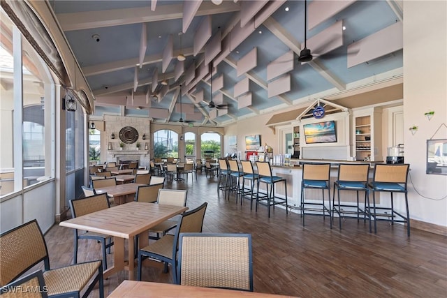 dining room featuring a ceiling fan, beamed ceiling, wood finished floors, and high vaulted ceiling