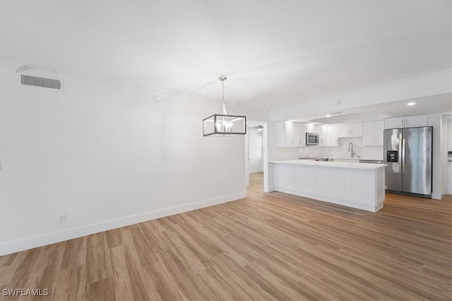 100 Estero Blvd Unit 633, Fort Myers Beach, FL 33931 - kitchen with stainless steel appliances, light countertops, a peninsula, white cabinets, and light wood-style flooring