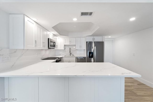 100 Estero Blvd Unit 633, Fort Myers Beach, FL 33931 - kitchen with stainless steel appliances, a sink, a peninsula, a raised ceiling, and recessed lighting