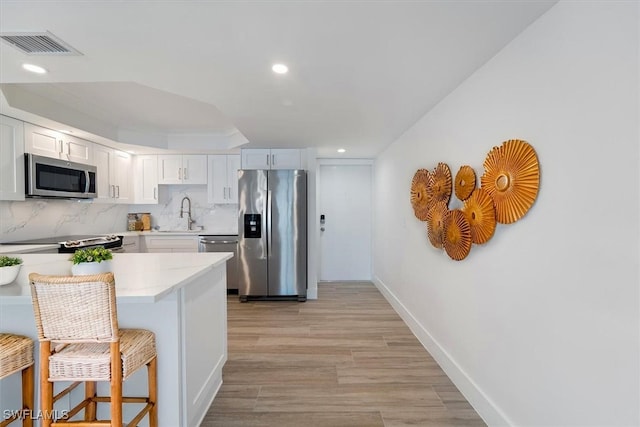 100 Estero Blvd Unit 633, Fort Myers Beach, FL 33931 - kitchen with appliances with stainless steel finishes, a breakfast bar area, light wood-style flooring, white cabinetry, and recessed lighting