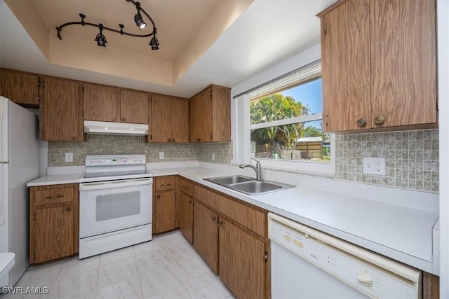 2590 Poinciana St, Naples, FL 34105 - kitchen with white appliances, a tray ceiling, under cabinet range hood, light countertops, and a sink
