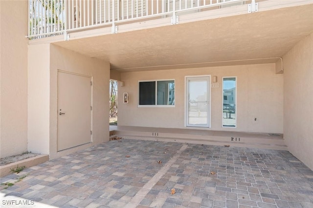 entrance to property with stucco siding and a patio