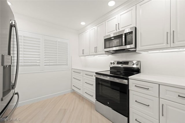 kitchen featuring appliances with stainless steel finishes, white cabinetry, light countertops, crown molding, and recessed lighting