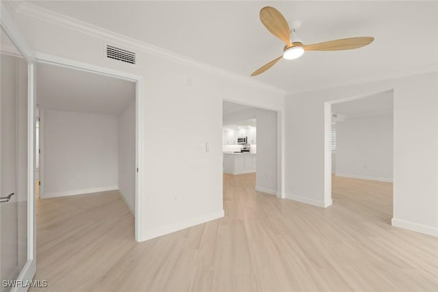 empty room featuring ornamental molding, ceiling fan, light wood-style flooring, and baseboards